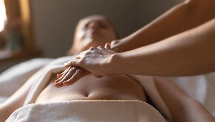 close up de mão unidas conduzindo terapia reiki em mulher deitada